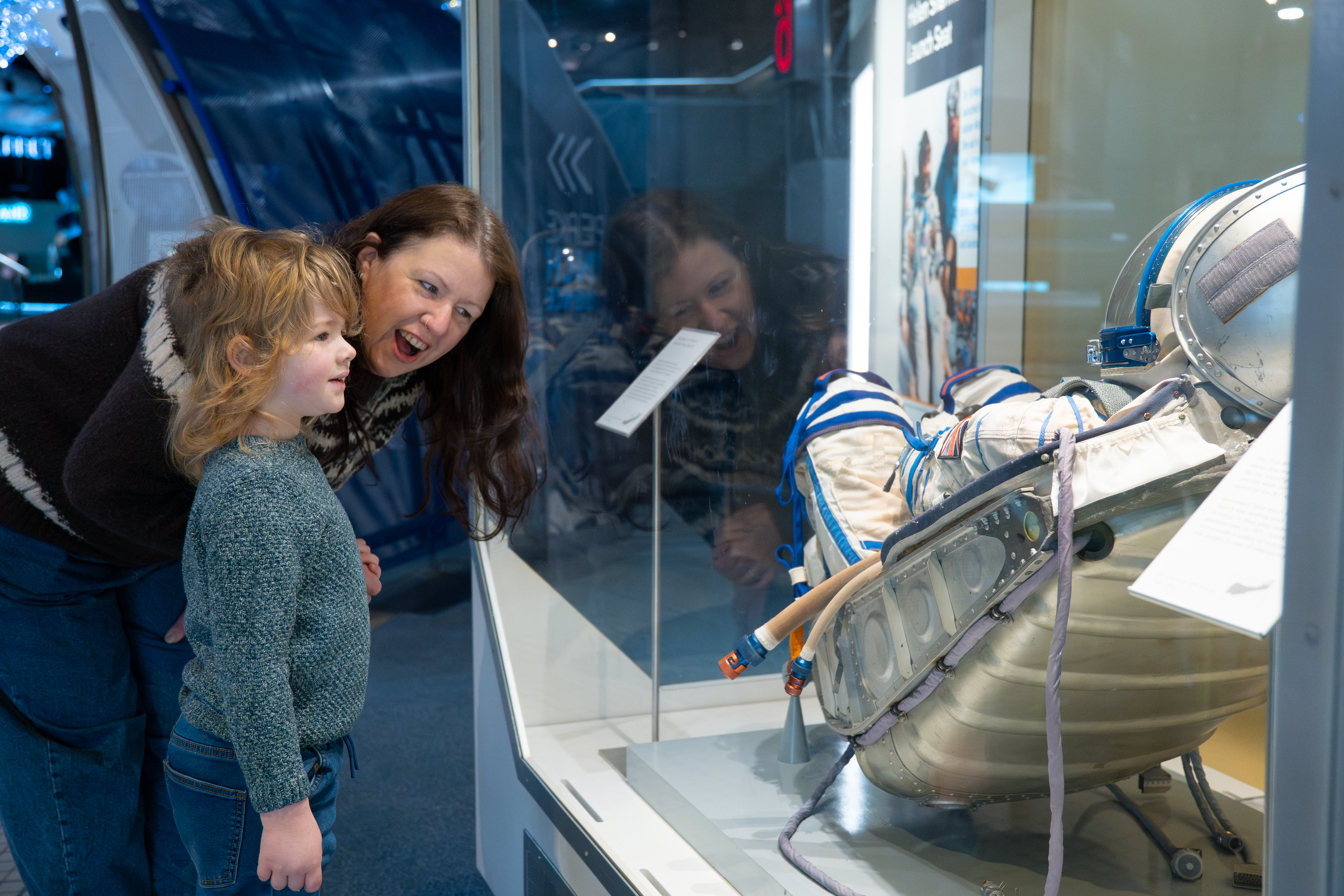 Young child and mother looking at Helen Sharman's launch couch in Into Space