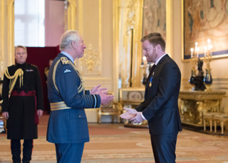 Brady receiving his OAM from King Charles at Windsor Castle.