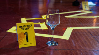 A wine glass and Crime and Dine Table topper on the floor in the galleries