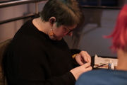 Lady looks closely at a figure she is painting at To Boldly Game