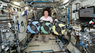 NASA astronaut Megan McArthur poses with the Astrobees onboard the ISS.