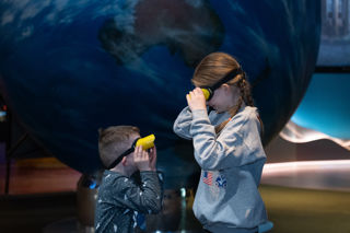 Two children in goggles looking at each other in Home Planet gallery