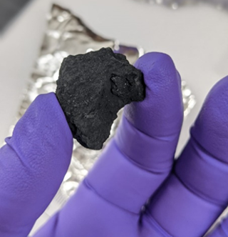Fragment of the Winchcombe meteorite held by a researcher. 