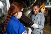 Education facilitator and teen in Into Space with an spacesuit glove science busk