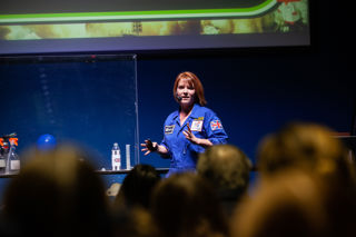 Education facilitator on LIVE Space stage presenting to a group of visitors