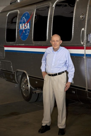 Retired astronaut Thomas P Stafford stands next to the NASA Astrovan.