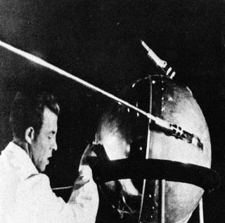 Photograph of a Russian technician putting the finishing touches on Sputnik 1, humanity's first artificial satellite.