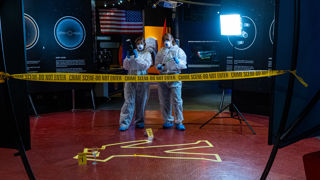Sarah and Laura standing in the galleries over a tape outline