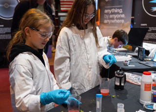 Two girls in white coats doing experiments at the UK In Space Festival