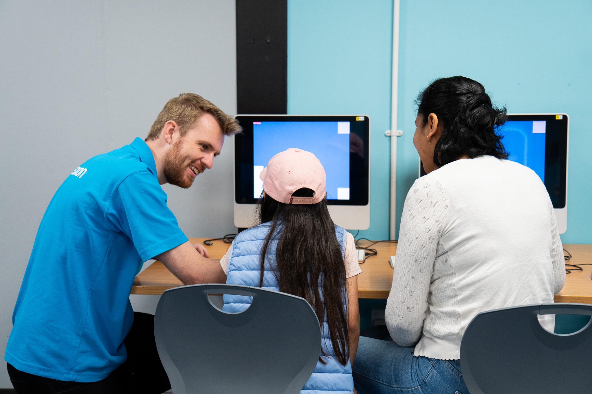 Mother and daughter on a computer with a member of the Education team during Home Education Day