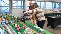 Family looking at a large LEGO train layout at the Brickish Weekend